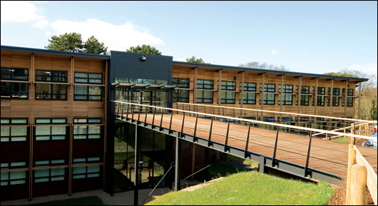 A commitment to conserving the environment in a broader sense was vital for the Orchard building, and two-thirds of the external cladding is cedar wood which blends well with the building's setting. Located in an eighteen acre woodland, the building's main entrance is across a footbridge A commitment to conserving the environment in a broader sense was vital for the Orchard building, and two-thirds of the external cladding is cedar wood which blends well with the building's setting. Located in an eighteen acre woodland, the building's main entrance is across a footbridge